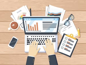 Businessman Working on Laptop With Documents, Coffee, and Pencil